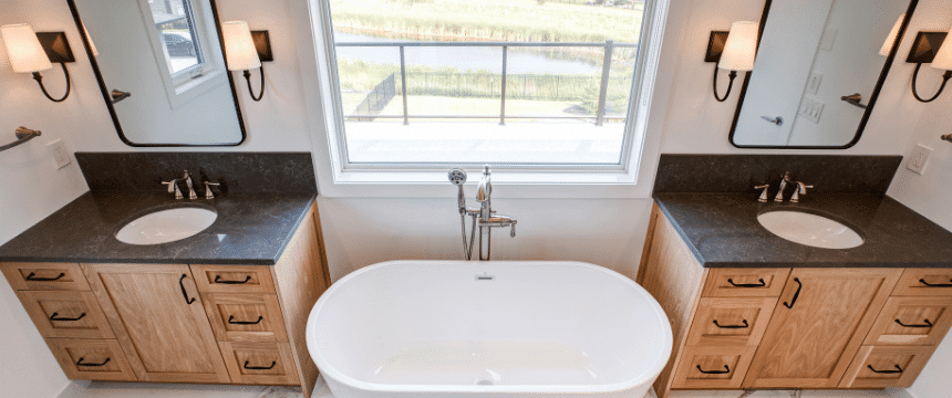 Dual vanity his and her space separated with a deep soaker tub, looking out over the backyard