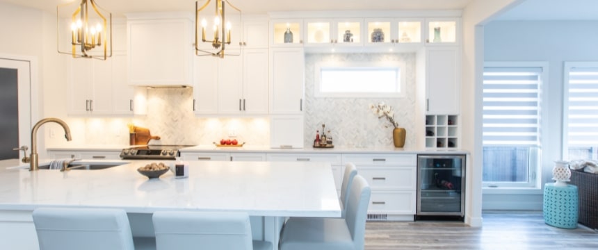 An elegant, showcase kitchen renovation with beautiful cabinetry that offers amazing storage, custom herringbone pattern tiles, and a large island with sink part of a home renovation in Winnipeg