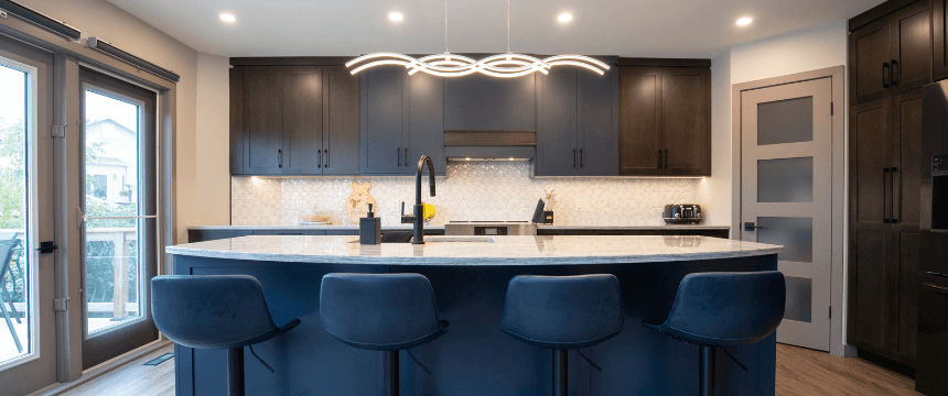 A modern kitchen renovation featuring dark flat-panel cabinetry, a curved island with seating, a patterned backsplash, and a glass patio door.