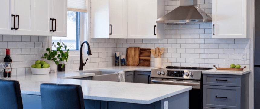 Renovating your forever home: A bright kitchen renovation with white upper cabinets, gray lower cabinets, a white subway tile backsplash, and an island with bar seating.